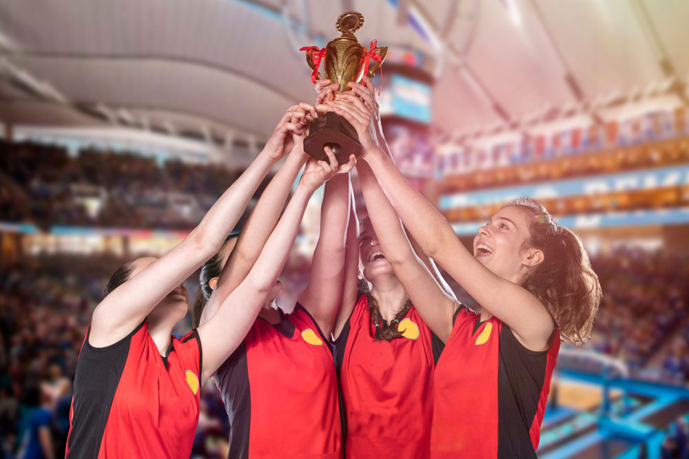 Four female volleyball players holding up a trophy