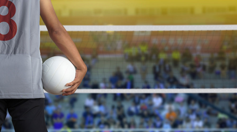 Volleyball player holding a ball looking at the net