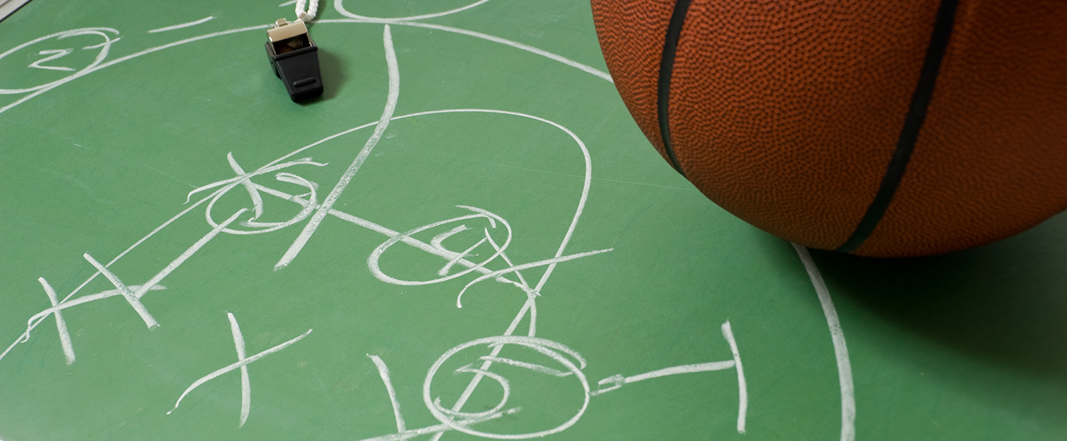 Basketball sitting on a chalkboard with a play written on it