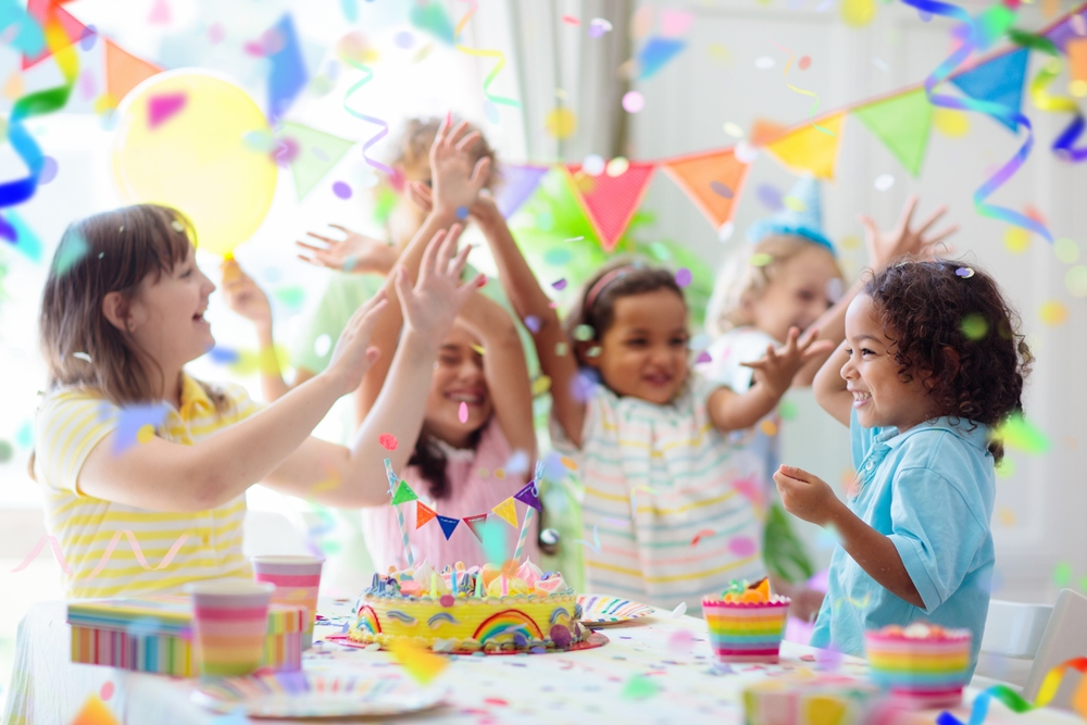 Children celebrate a birthday with a colorful cake and gifts