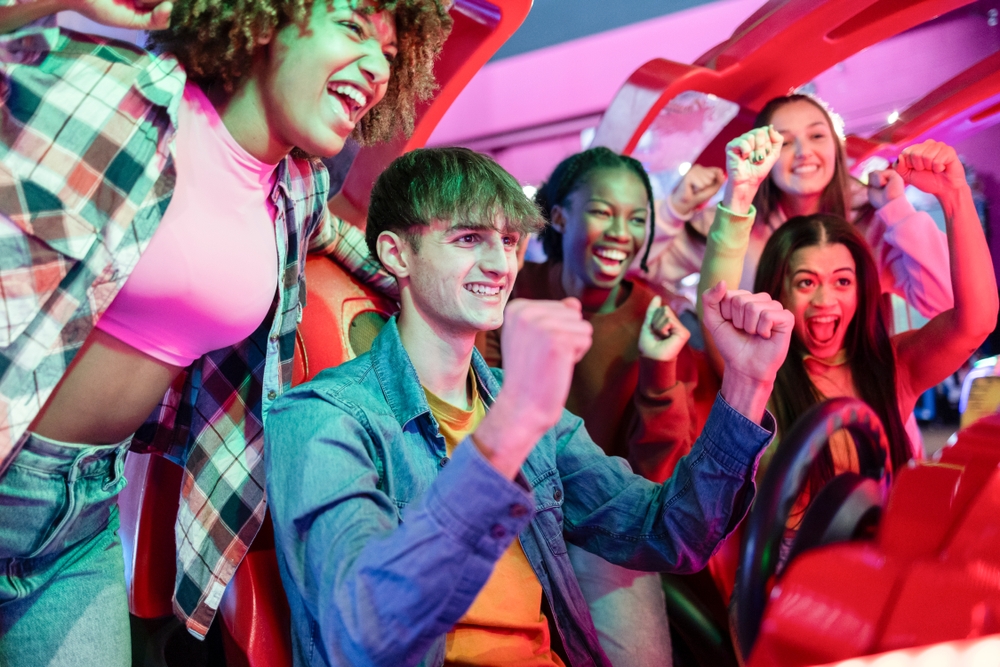 Group of friends celebrate a winning moment while playing an arcade racing game