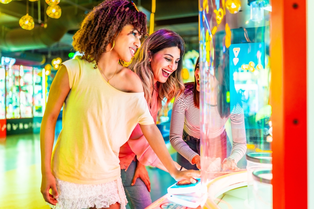 Three smiling female friends enjoying their time together in an arcade