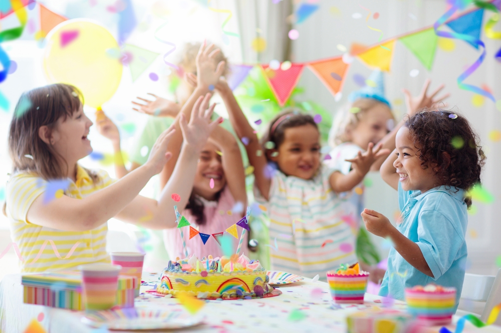 Children celebrating a birthday with a colorful cake and gifts