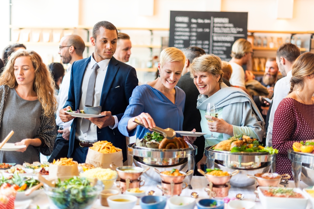 People enjoying a buffet with a variety of dishes at a social event
